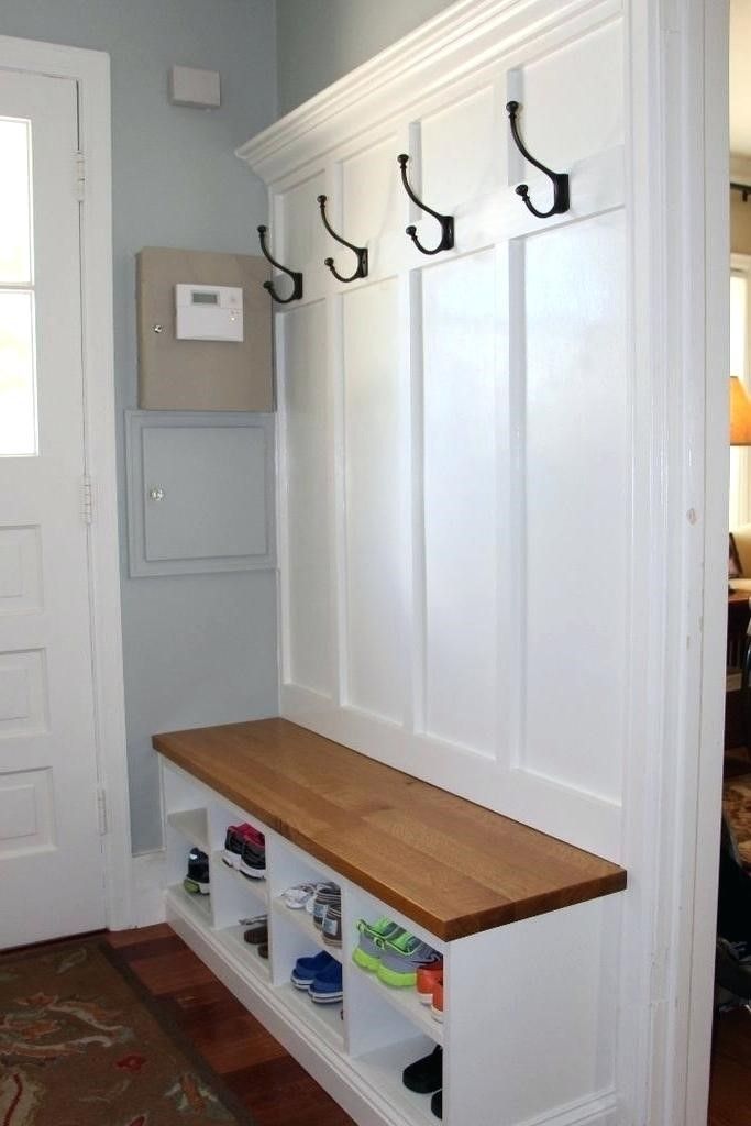 a white coat rack with hooks and shoes on the bottom shelf next to a door