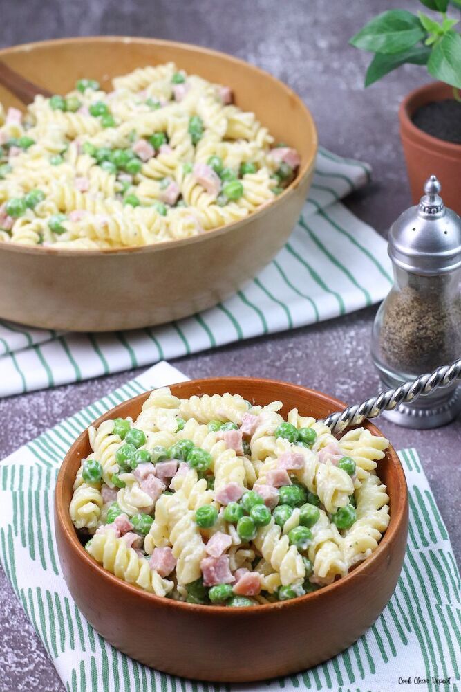 two bowls filled with pasta and peas on top of a table