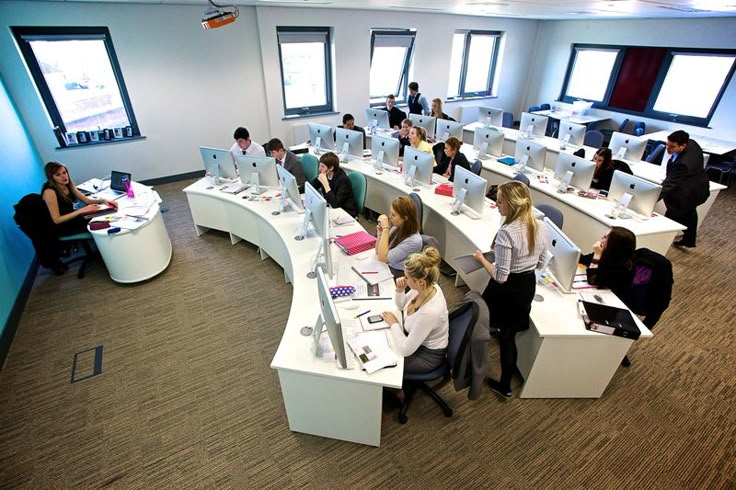 there are many people sitting at desks in this office setting, working on computers