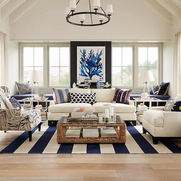 a living room filled with white furniture and lots of blue accents on the walls in front of large windows