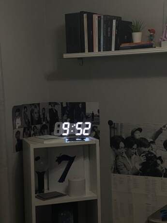 an alarm clock sitting on top of a white shelf next to a bookcase with books