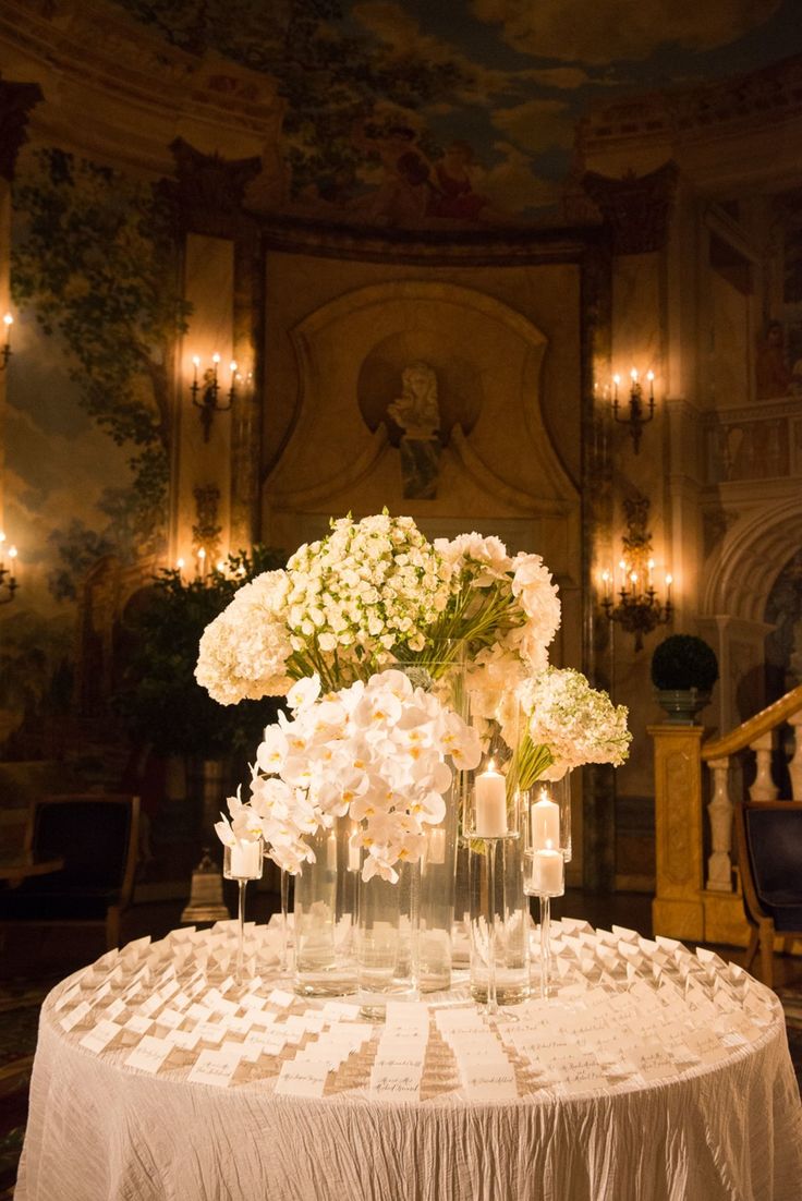 a table with flowers and candles on it in front of a chandelier filled with lights