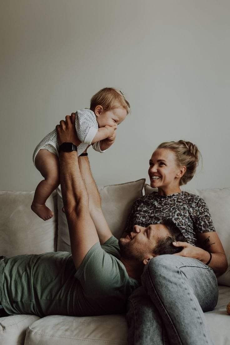 a man and woman sitting on a couch with a baby