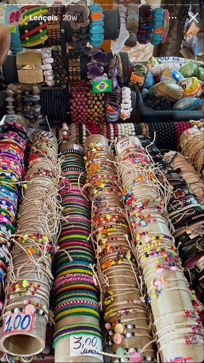 many different bracelets are on display in a market place with price tags attached to them