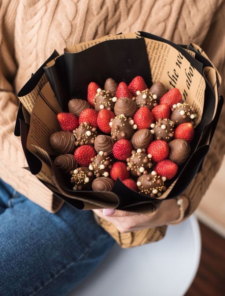 a woman holding a bouquet of strawberries and chocolate covered strawberries in her hands