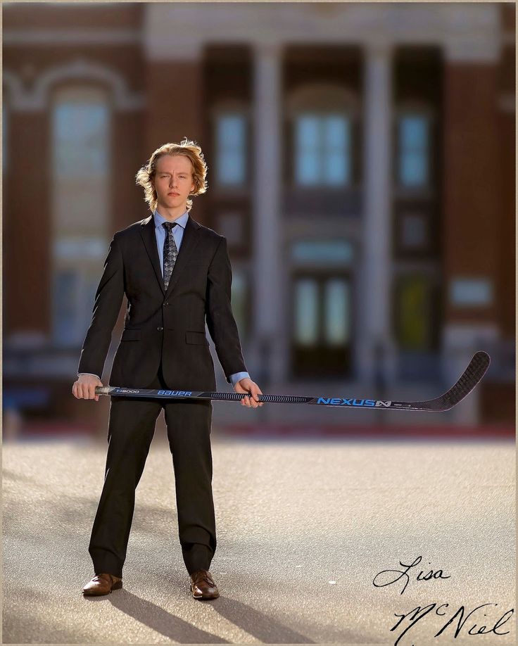 a man in a suit and tie holding a hockey stick with his hands behind his back