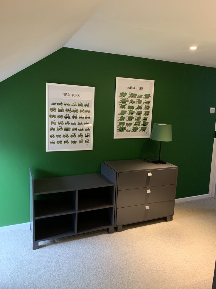 a room with green walls and two pictures on the wall, one has a gray filing cabinet