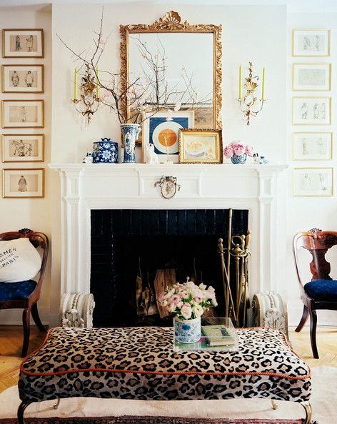 the living room is decorated in leopard print and pink flowers are on top of the fireplace mantel