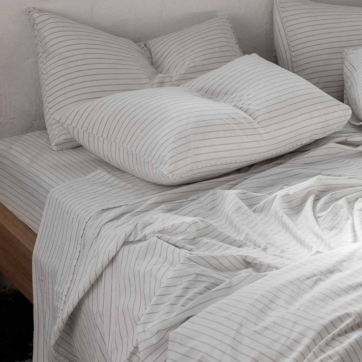 an unmade bed with white sheets and pillows