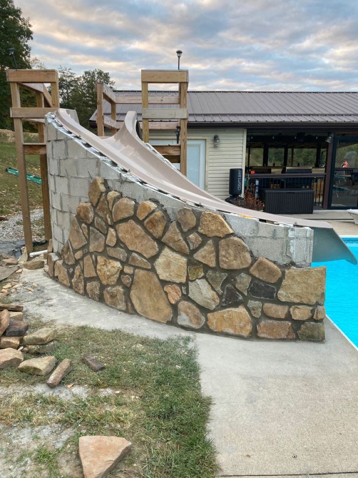 a stone wall next to a swimming pool