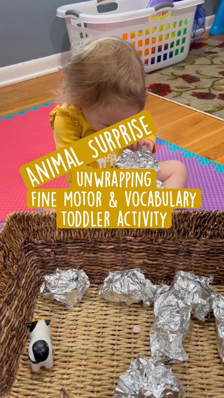 a toddler is playing with tin foil and looking at an animal in the basket