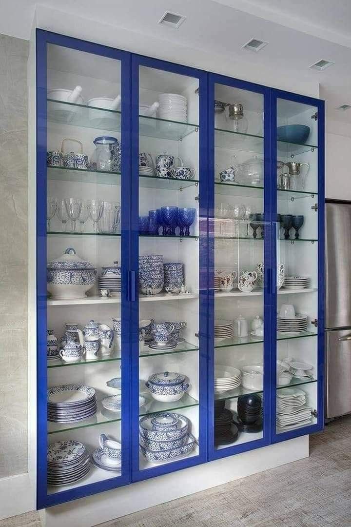 a blue and white china cabinet with glass doors on the front is filled with dishes