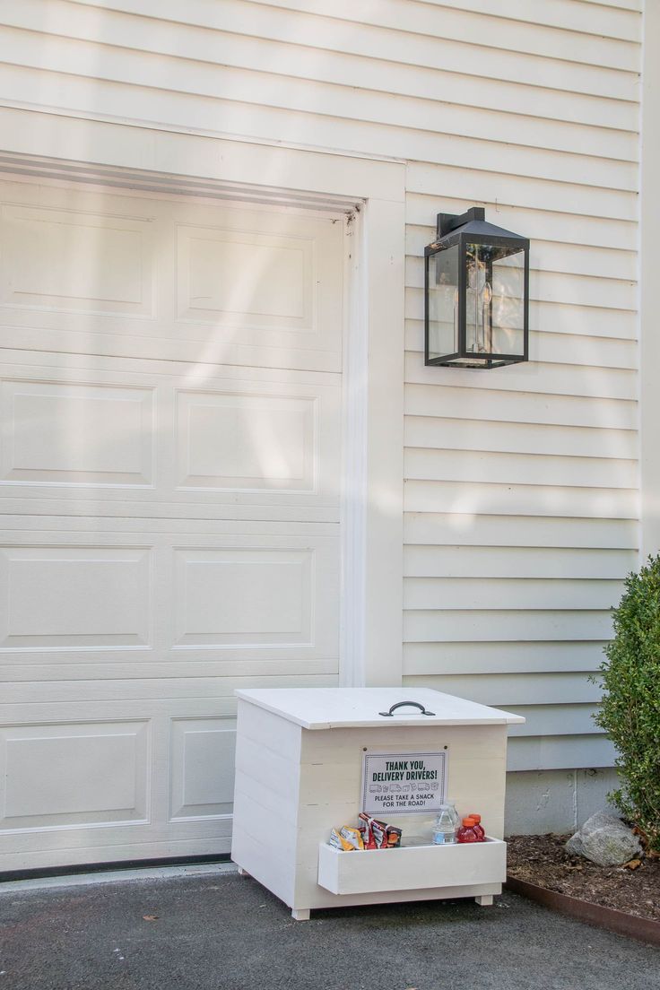 a white box sitting in front of a garage with a light on it's side