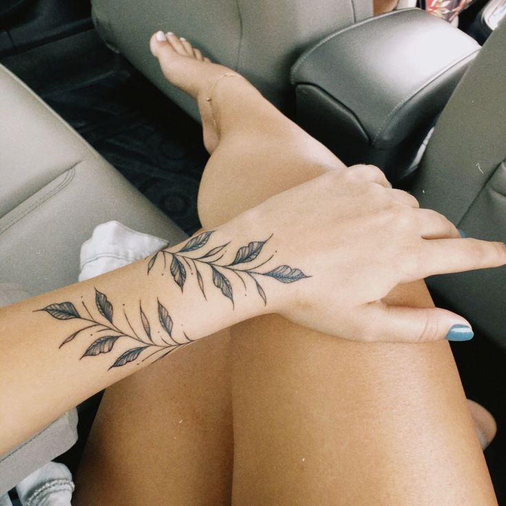 a woman's arm with a tattoo on it sitting in the back seat of a car