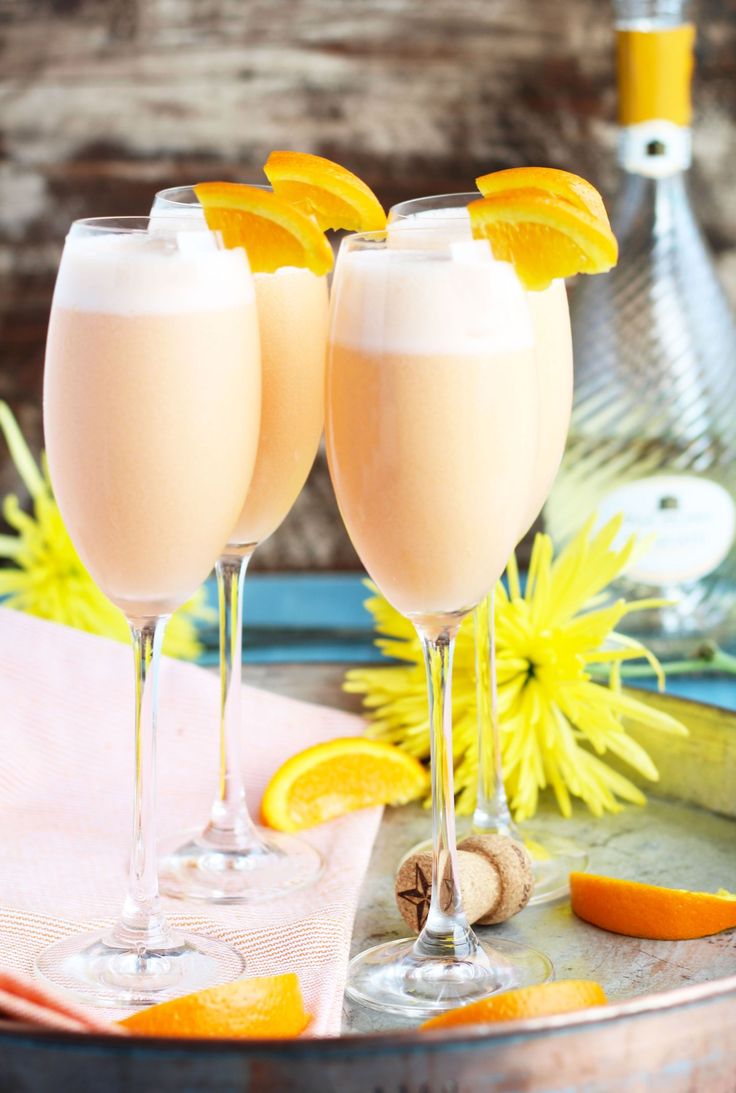 pineapple orange creamsice mimos are served in wine glasses on a tray