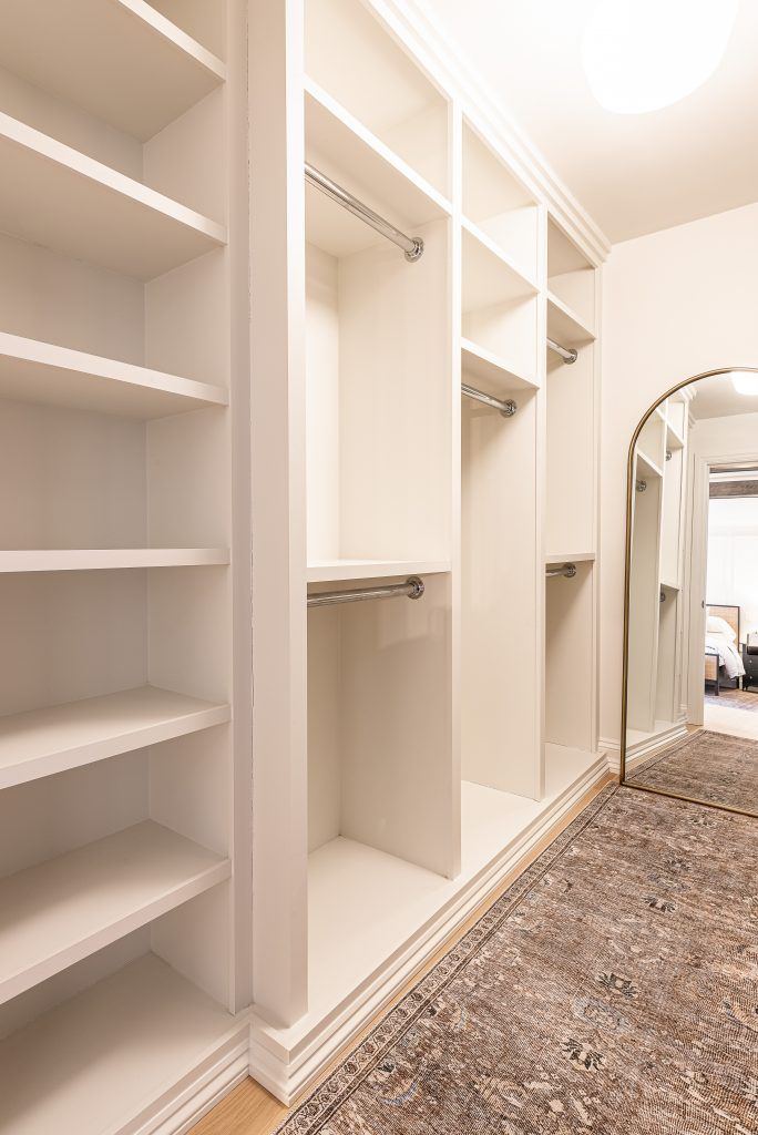 an empty walk in closet with white shelves