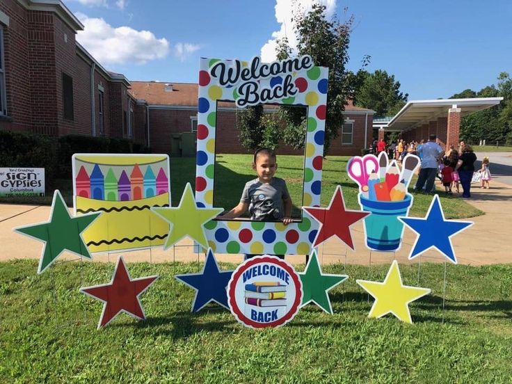 a young boy standing in front of a welcome back sign with star decorations on it