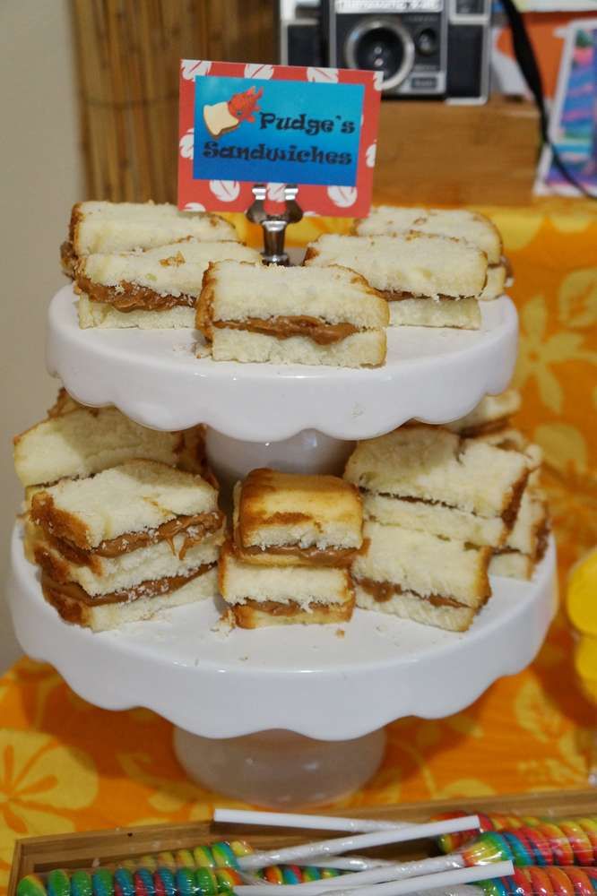 there are many sandwiches stacked on the cake platter with an orange and yellow table cloth