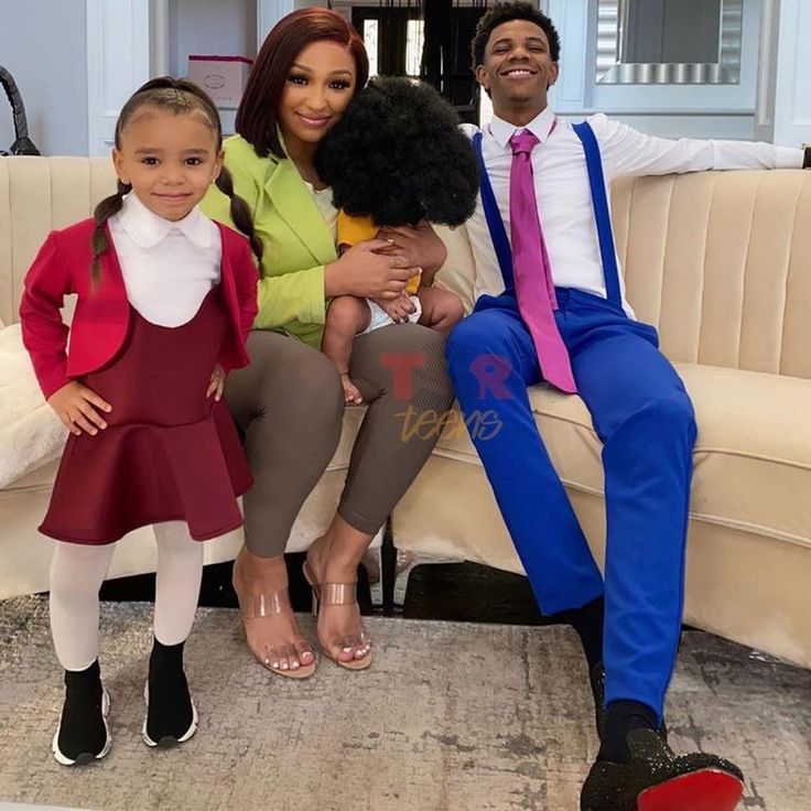 a man and two children sitting on a couch in front of a white couch with a pink tie