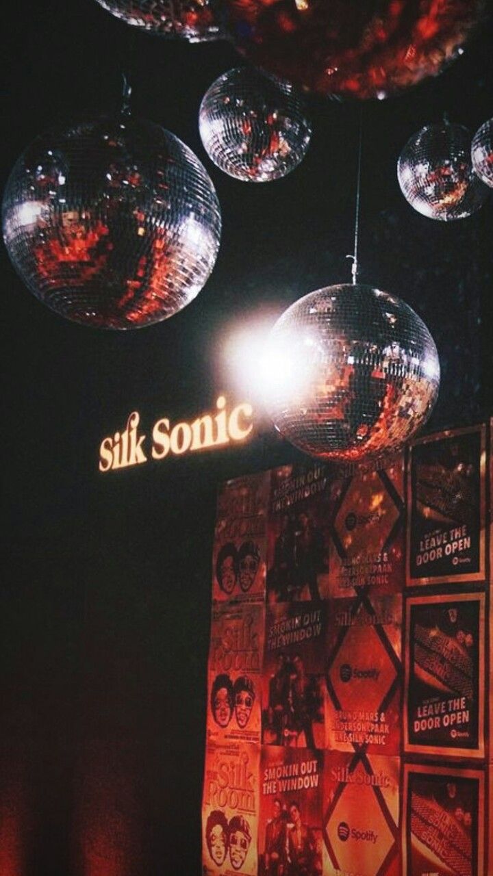 disco balls hanging from the ceiling in front of a sign that says silk sonic on it