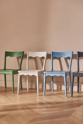 five chairs lined up against a wall in different colors and sizes, all on one side of the room