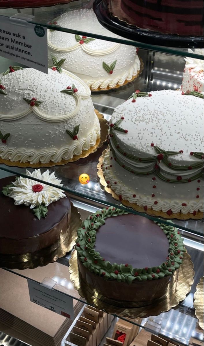 several cakes on display in a glass case with frosting and sprinkles