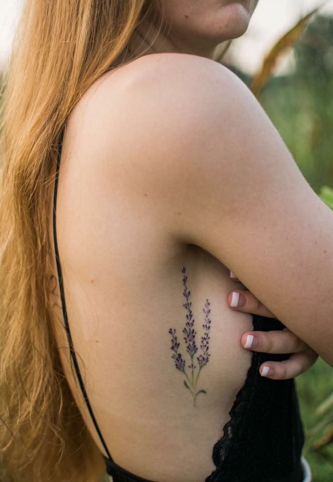 the back of a woman's shoulder with a lavender tattoo on her left arm