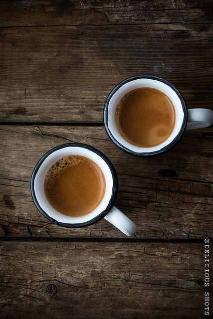 two cups of coffee sitting on top of a wooden table