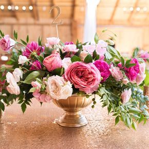 a vase filled with pink and white flowers sitting on top of a table next to candles