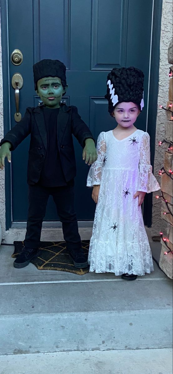 two children dressed up as zombies standing in front of a door