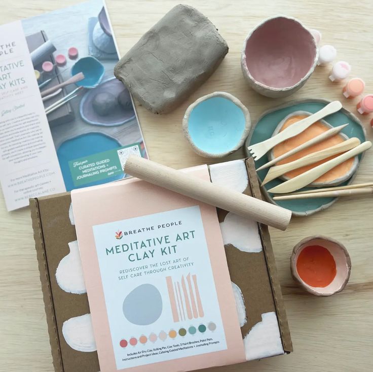 some craft supplies are laying out on a wooden table with paint, paper and other items