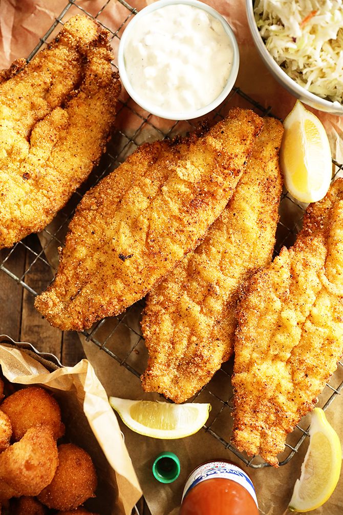 fried fish and coleslaw are served on a wire rack with dipping sauces