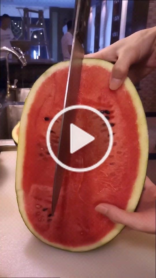 someone cutting up a piece of watermelon with a large knife on top of it