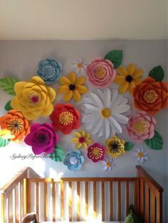 a crib in front of a wall with paper flowers on it