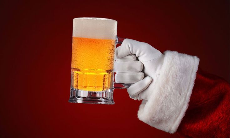 a person in a santa claus outfit holding a mug of beer with foamy liquid