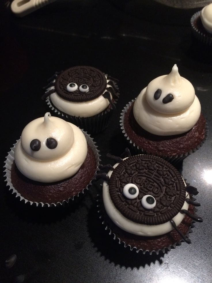 four cupcakes with white frosting and chocolate decorations