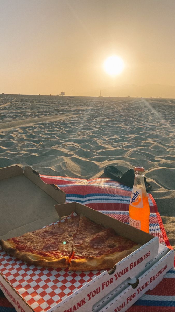 a pizza sitting on top of a red and white checkered blanket next to a bottle