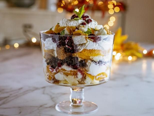 a glass bowl filled with fruit salad on top of a marble counter next to a christmas tree