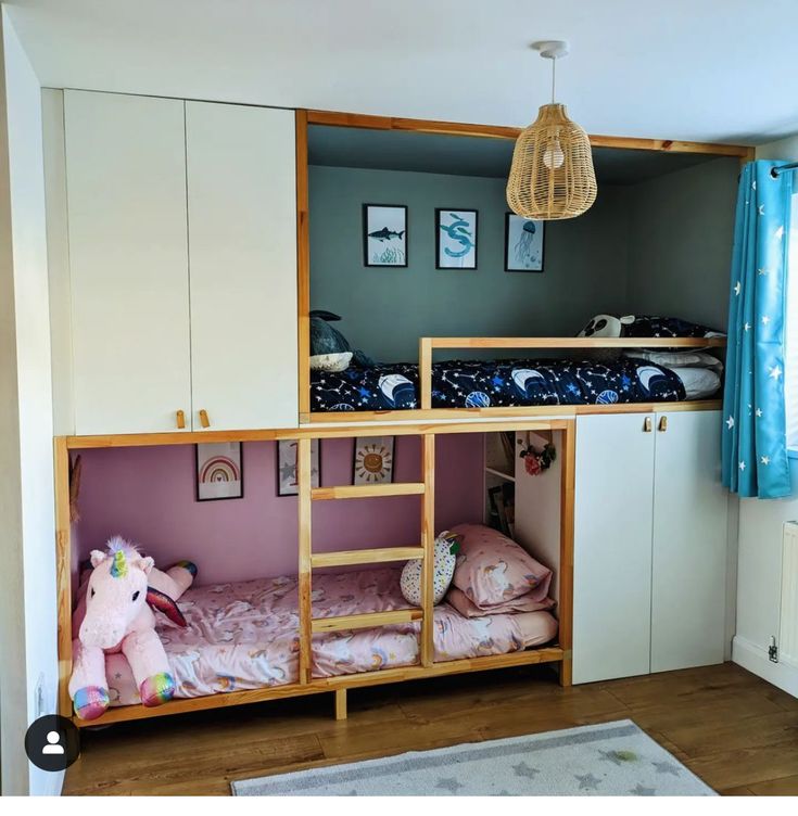 a bunk bed in a room with blue curtains and pink bedspread on the floor