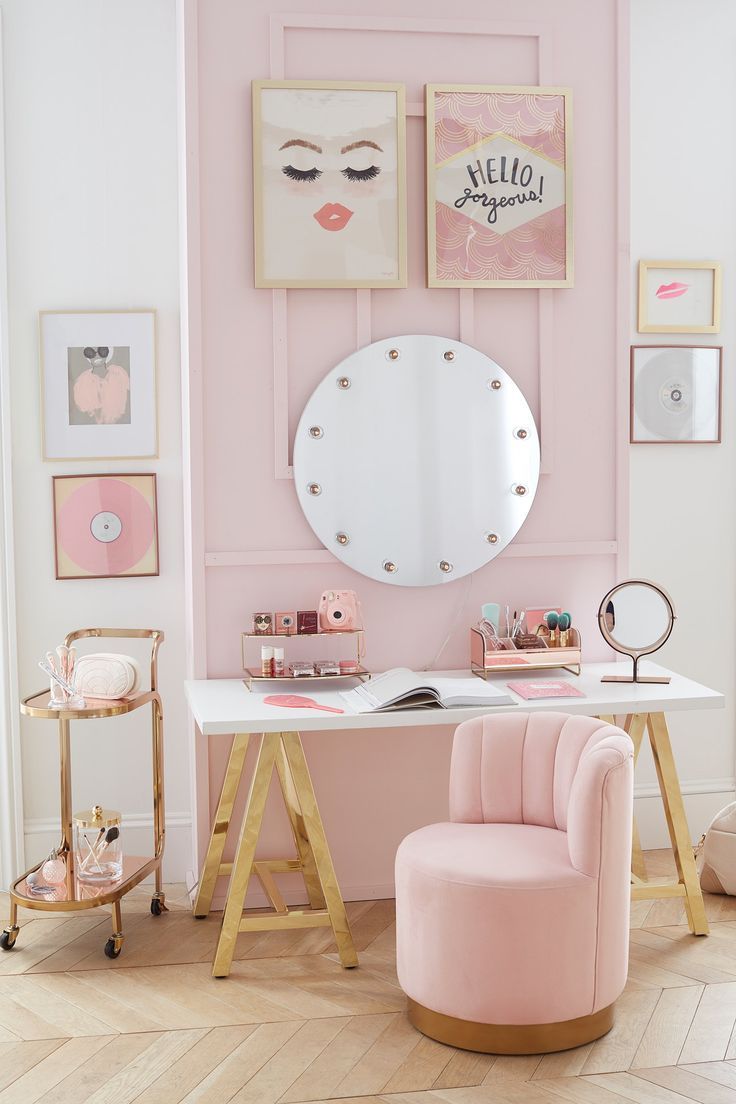 a pink room with pictures on the wall and a chair in front of a mirror