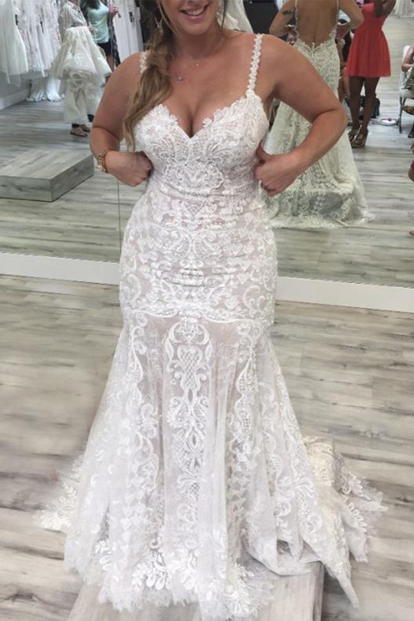 a woman standing in front of a mirror wearing a wedding dress