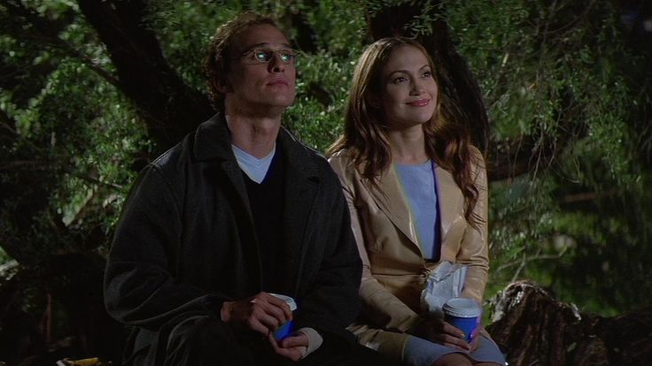 a man and woman sitting next to each other on a bench in the woods at night