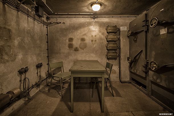 a table and two chairs in a room with exposed pipes on the wall behind it