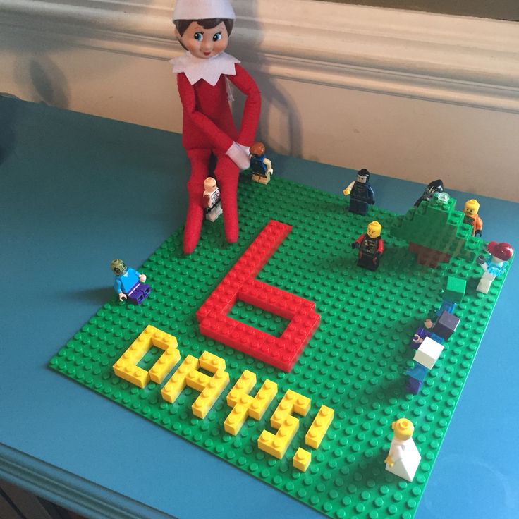 an elf is sitting on top of a lego table with letters and people around it