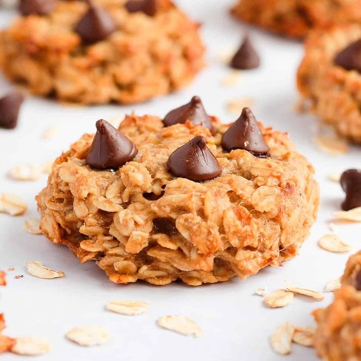 an oatmeal cookie with chocolate chips is on a white surface surrounded by almonds