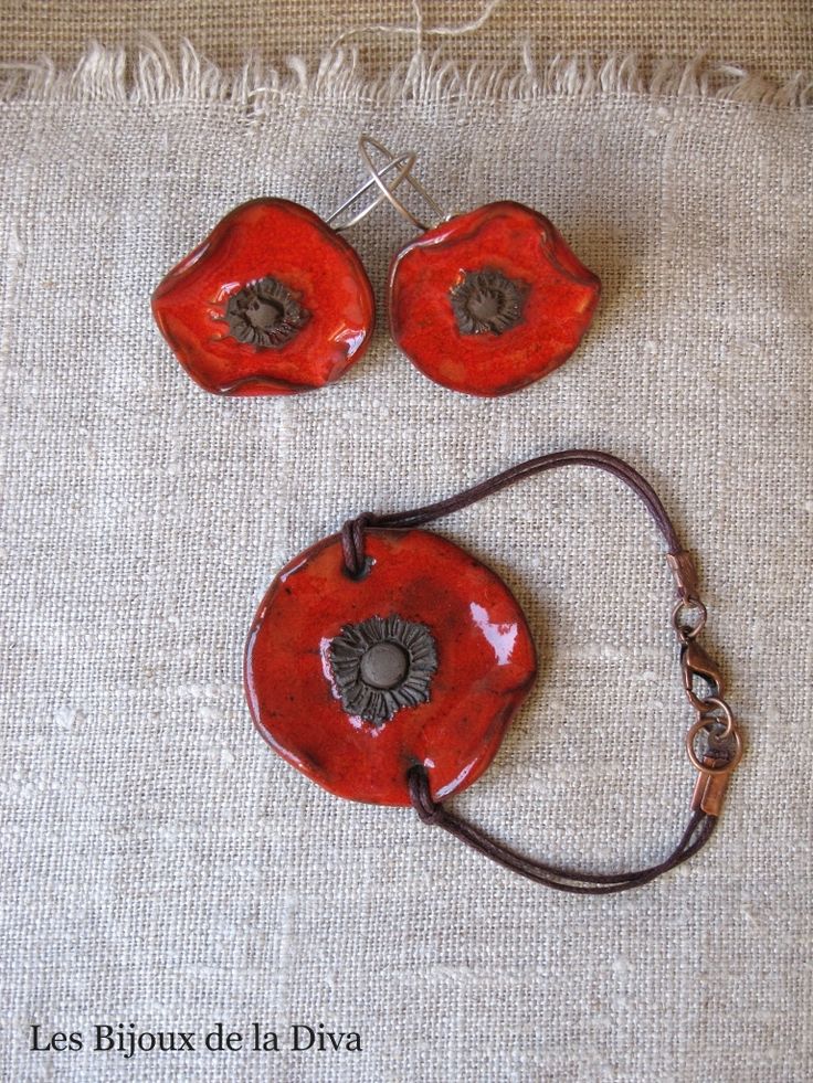 two pieces of red pottery sitting on top of a white cloth covered floor next to each other