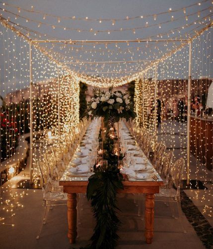 a long table is set up with lights and greenery