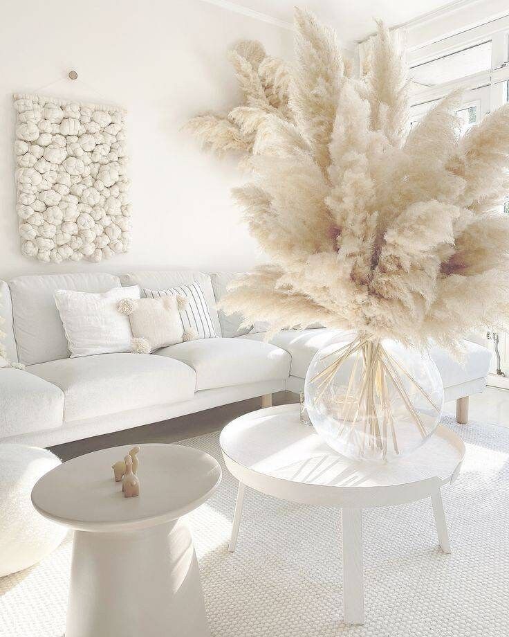 a living room filled with white furniture and lots of flowers in a vase on top of a table