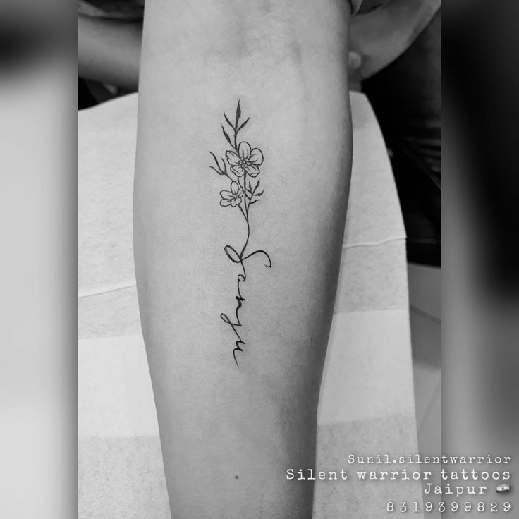 a woman's leg with a small flower tattoo on the left side of her arm