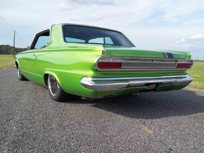 the green car is parked on the side of the road in front of some grass